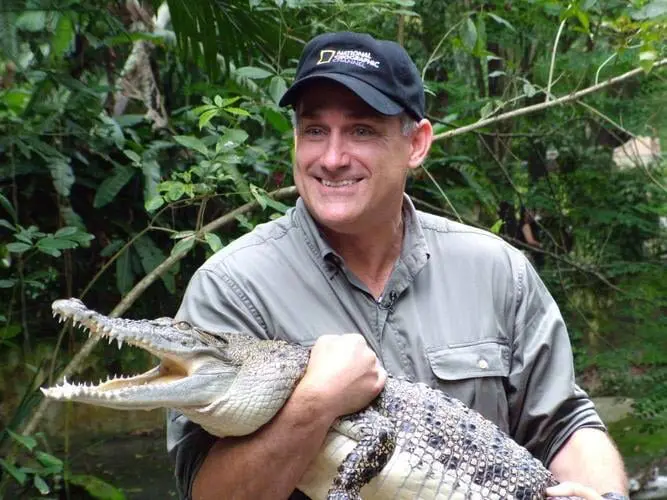 A man holding an alligator in his arms.