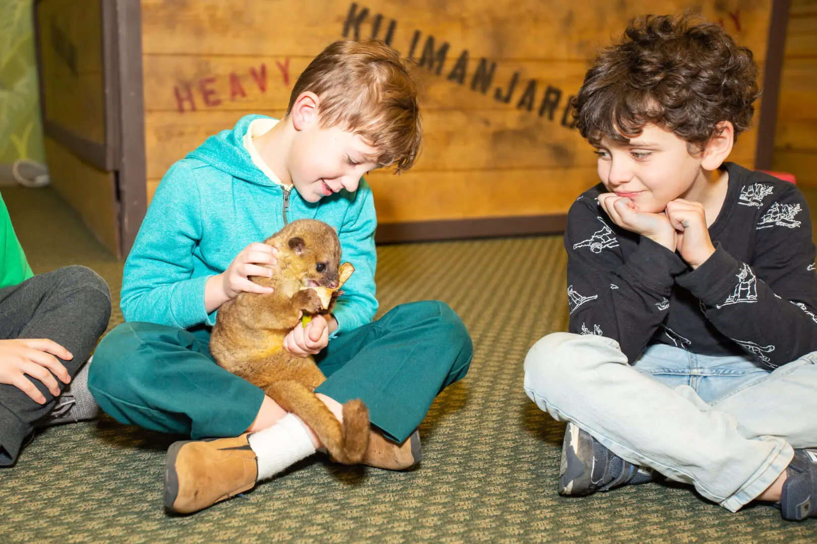 Two boys sitting on the floor with a stuffed animal.