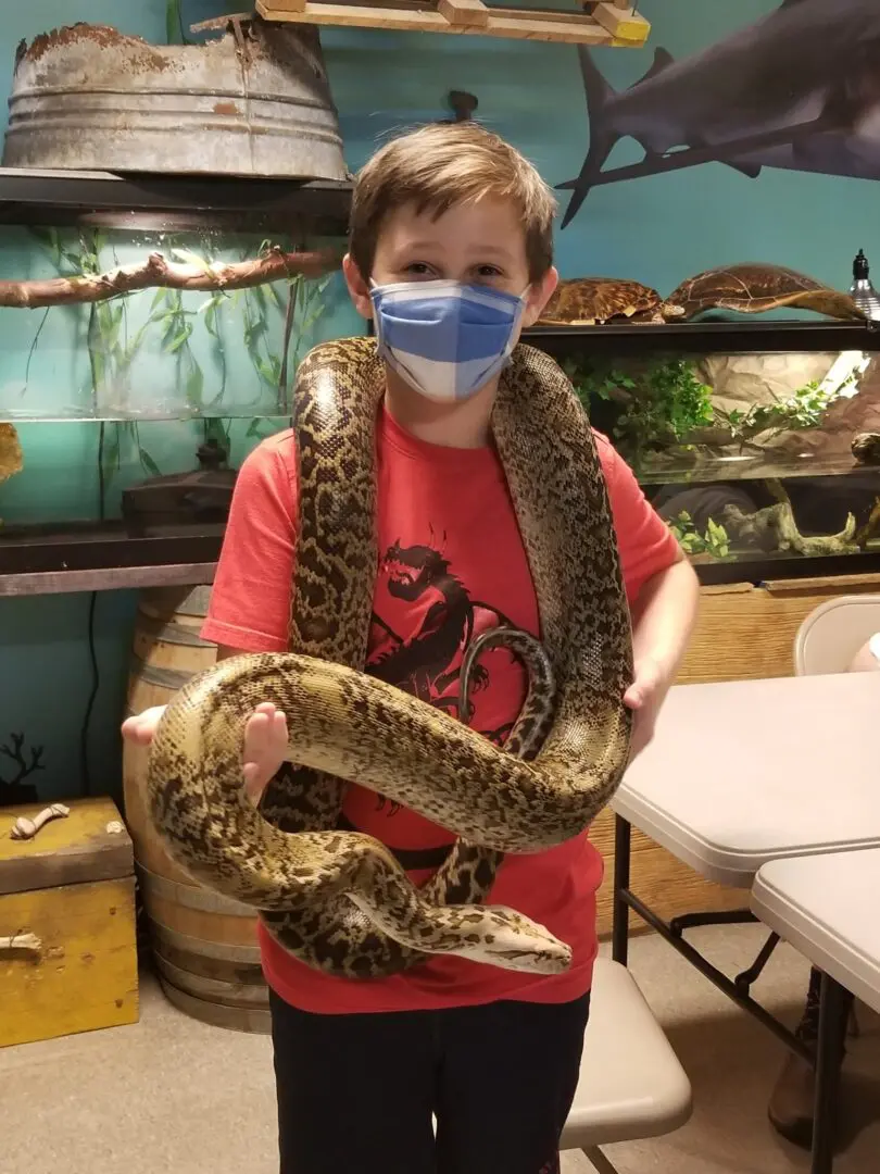 A boy holding a snake in his hands.