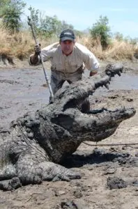 A man in the mud with an alligator.