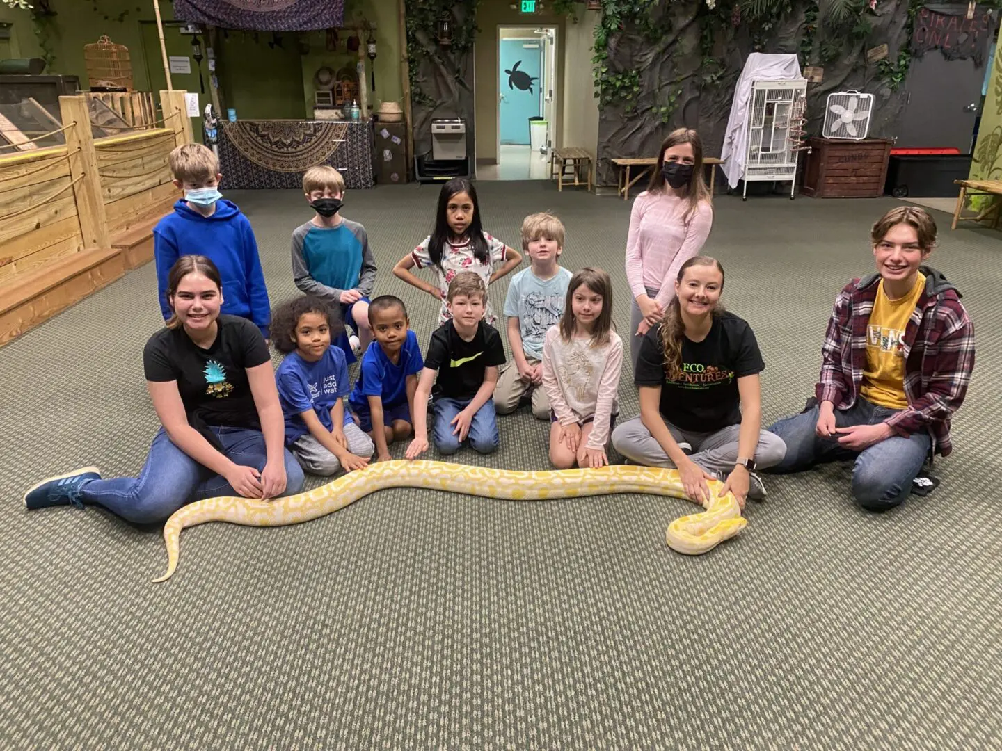 A group of people sitting around a snake.