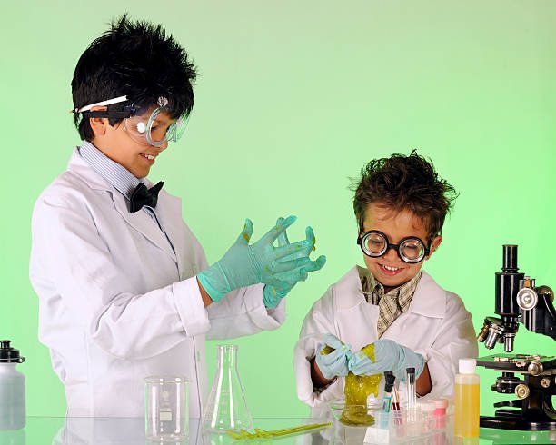 A preteen having fun with his preschool brother in a chemistry lab, both working as "mad scientists."