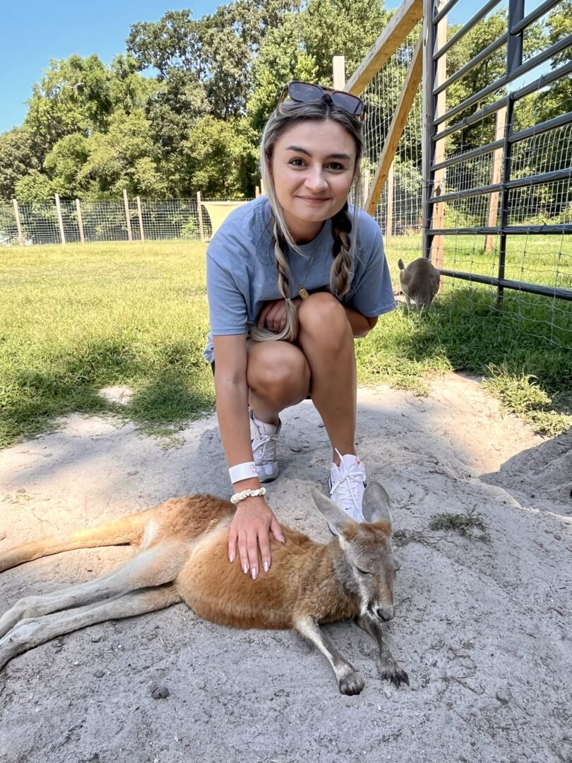 A girl kneeling down next to a dead animal.