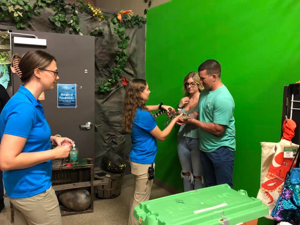 A group of people standing around in front of a green screen.