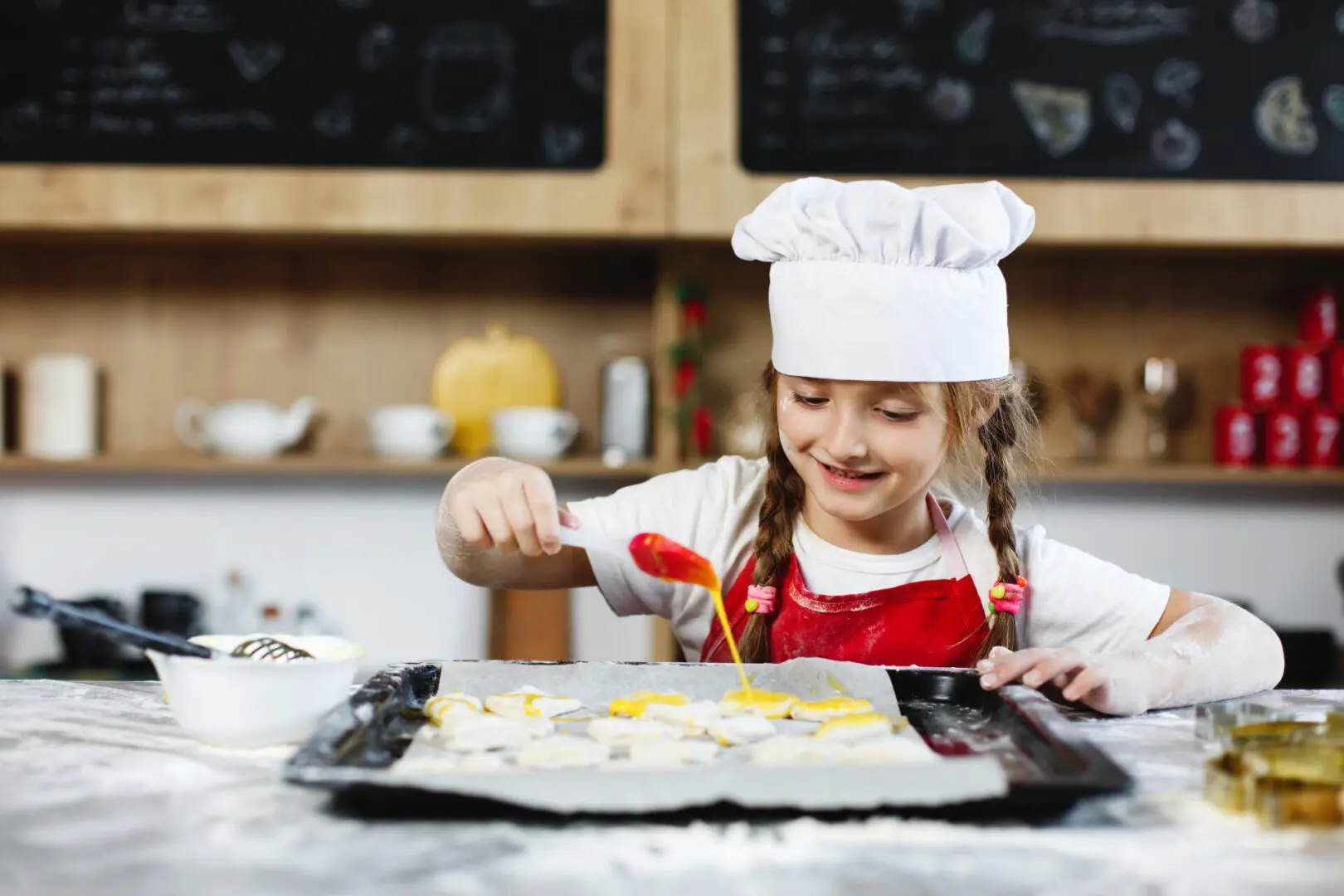 Little chief. Mom and daughter have fun preparing cookies with milk at a dinner table in cosy kitchen