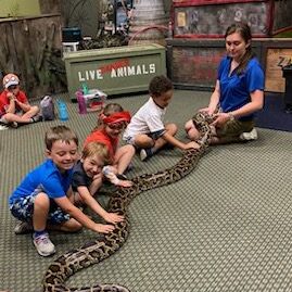 A group of children sitting around a snake.